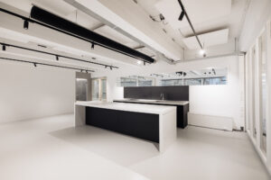 Moderne, minimalistische keuken in een kantoorruimte aan de Generaal Vetterstraat met zwart-wit keukeneiland en strakke afwerking.
